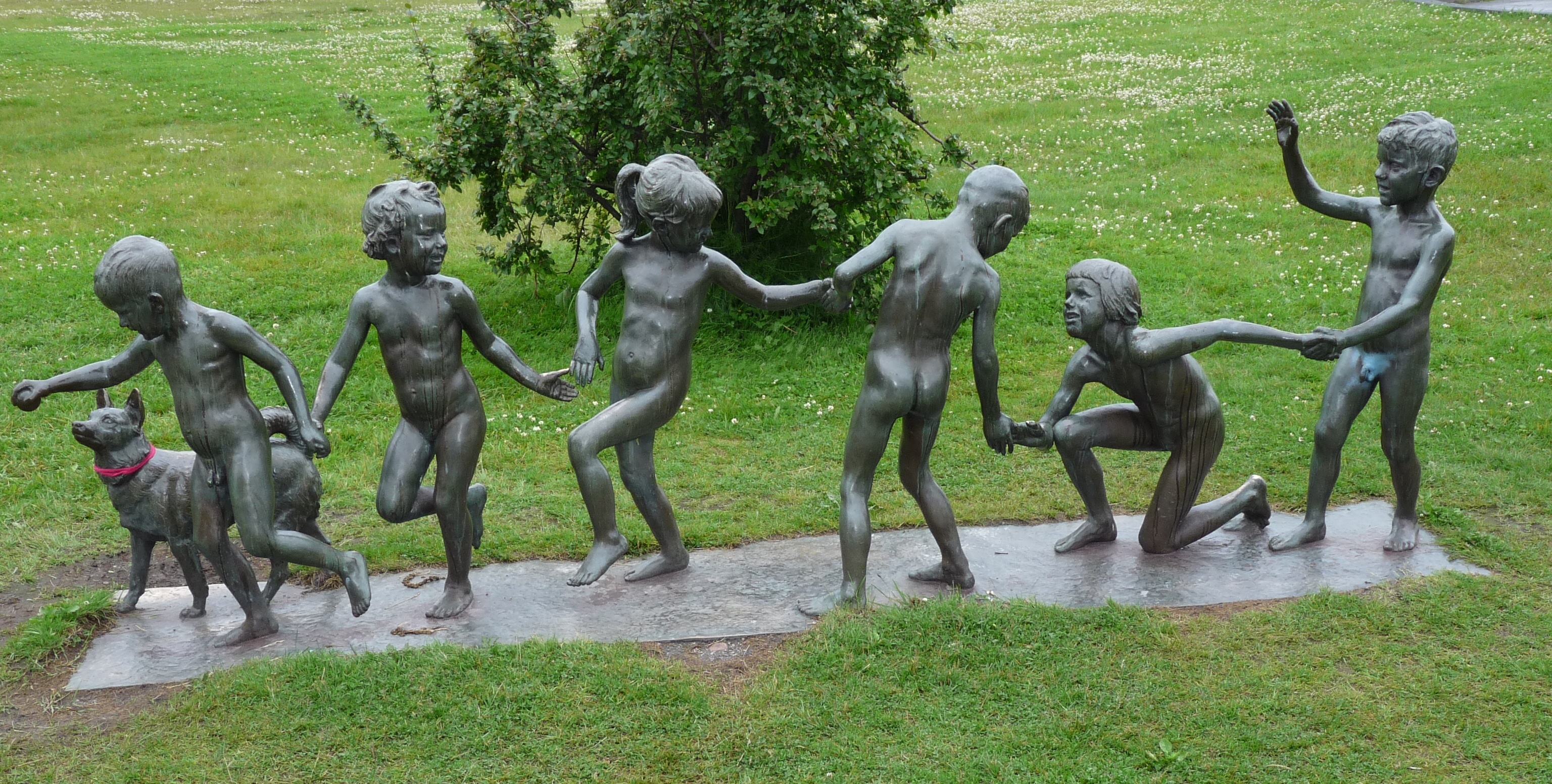 Statuen von spielenden Kindern mit Hund auf einer Wiese