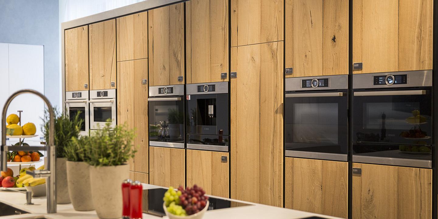 verschiedene Einbau-Küchengeräte in einer mit Holz verkleideten Wand