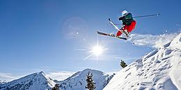 Skifahrer im Sprung, Schnee und Berge im Hintergrund