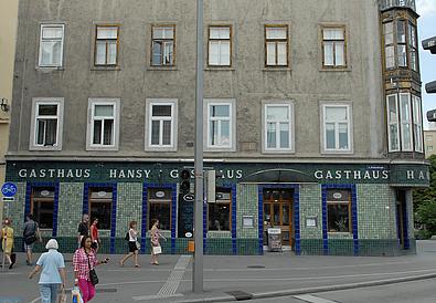 Sommerlich gekleidete Menschen auf der Straße vor dem Gasthaus