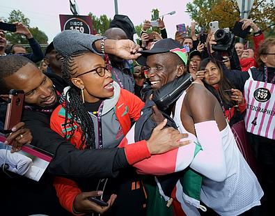 Kipchoge mit seiner Frau und einer jubelnden Menge