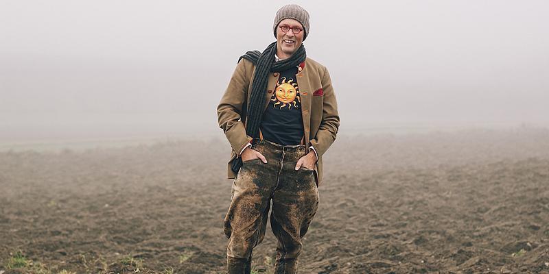 Johannes Gutmann mit Lederhose im Acker stehend