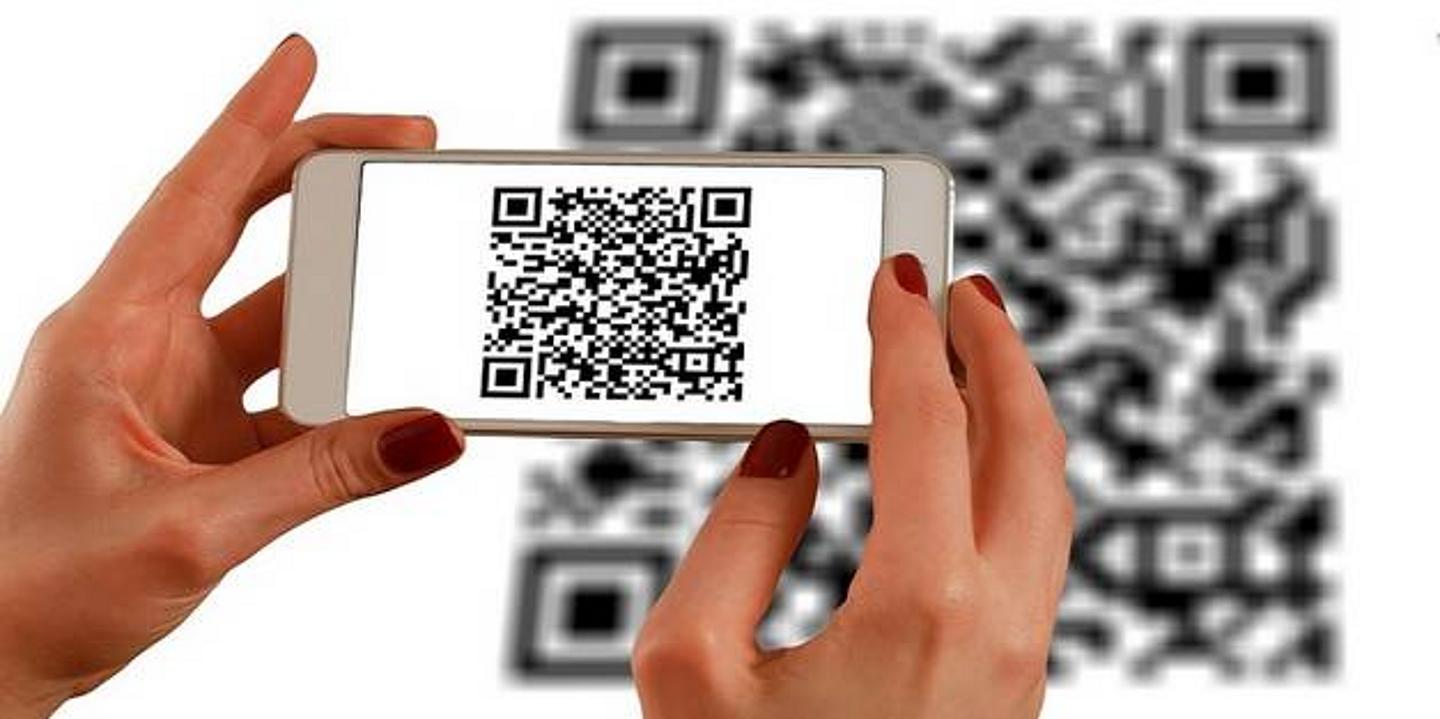 Frau hält Handy über QR Code