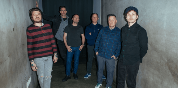 Die Bandmitglieder der Dropkick murphys stehen in einem schwach beleuchteten Gang