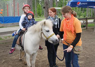 Zwei Mädchen sitzen auf einem weißen Pony