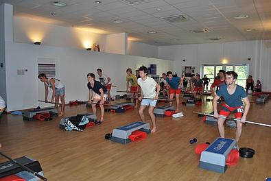 Schüler beim Fintesstraining mit Hantelstangen. 