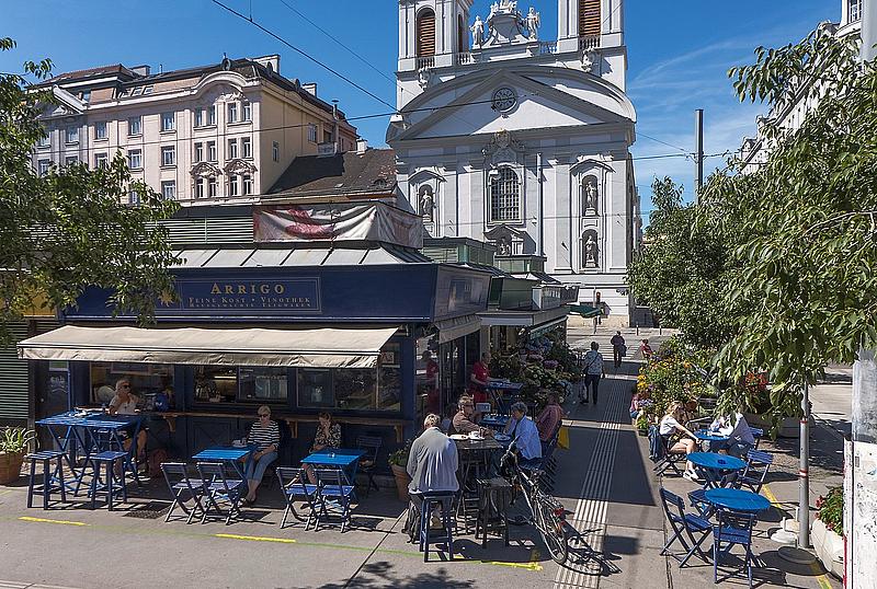 Menschen sitzen im Café Arrigo am Rochusmarkt in Wien