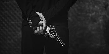 James Bond mit Rücken zur Kamera, hält eine Pistole in der Hand