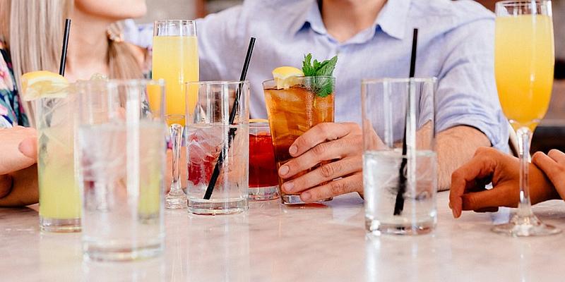 Menschen sitzen an einem Tisch und trinken Alkohol