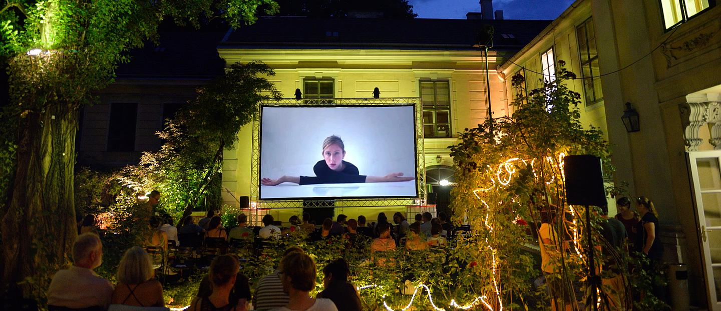 Menschen sitzen im Freien und schauen sich einen Film an.