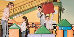 Eltern die mit ihren Kindern in einem Indoor-Spielplatz spielen