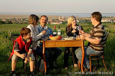 Eine Familie isst und trinkt im Weingarten