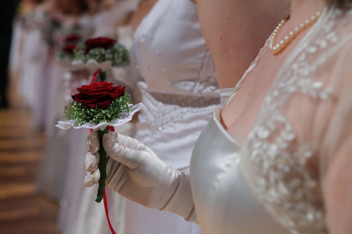 Debütantinnen im weißen Ballkleid mit Blumensträussen.