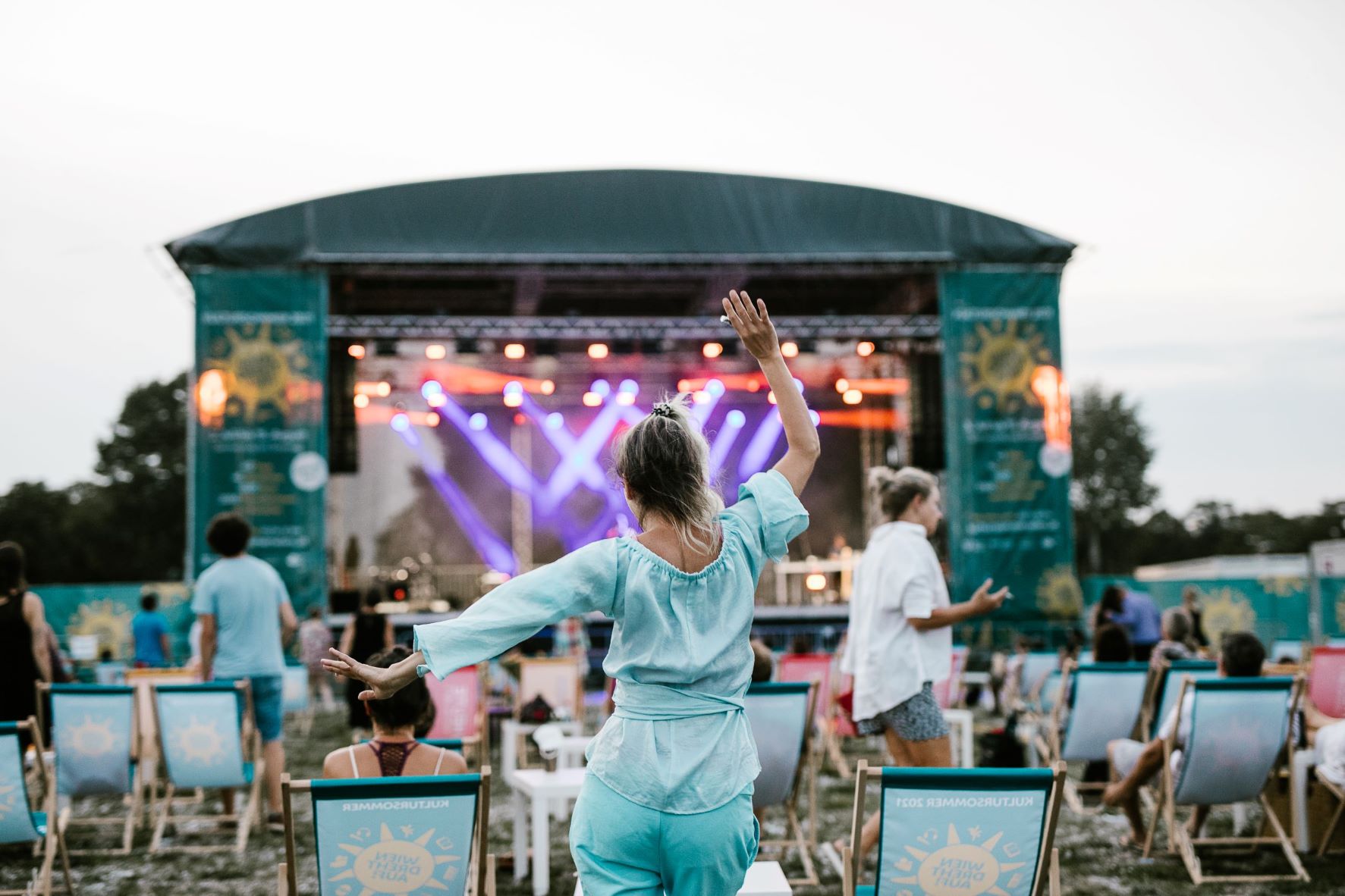 Frau tanzend von hinten, im Hintergrund eine der Wiener Kultursommer-Bühnen