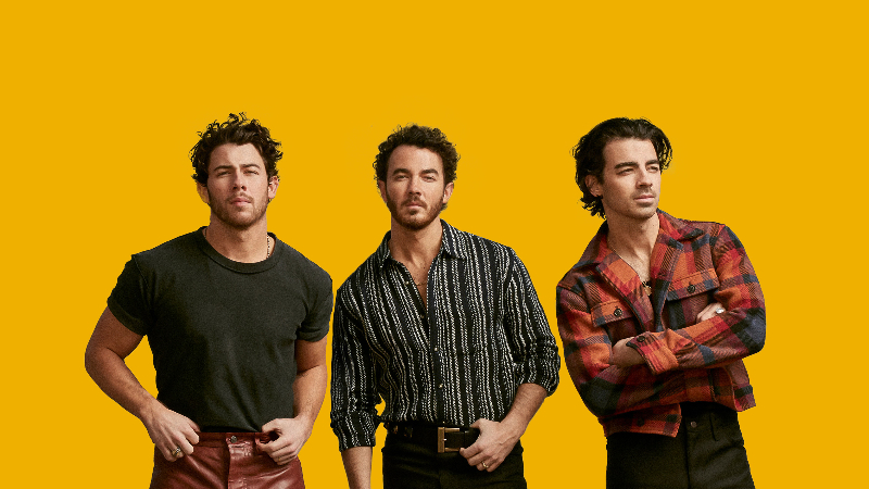 Die Band "Jonas Brothers" vor einem orangen Hintergrund