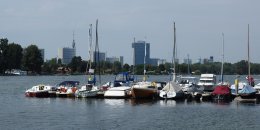 Das Bild zeigt Segelboote auf der Alten Donau, im Hintergrund ist das Vienna International Centre zu sehen.