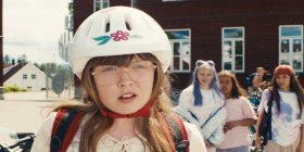 Mädchen mit großer Brille und Fahrradhelm, im Hintergrund ihre Mitschülerinnen