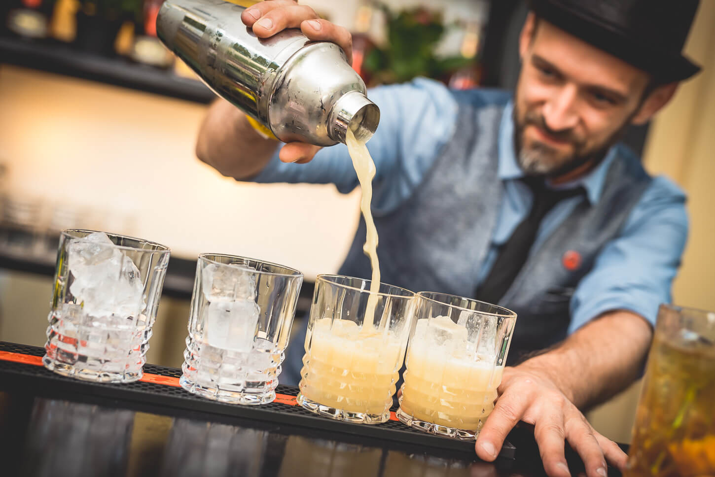 Barista schenkt aus Cocktail-Shaker in Gläser ein