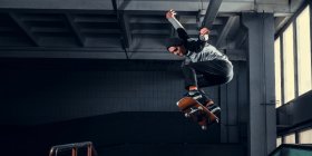 Skateboarder springt hoch auf einer Minirampe im Indoor-Skatepark