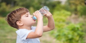 Kleine Bub trinkt gierig Wasser aus Flasche