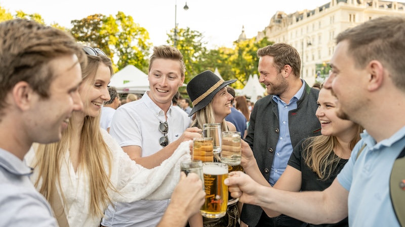 Menschengruppe, die mit Bierkrügen anstößt.