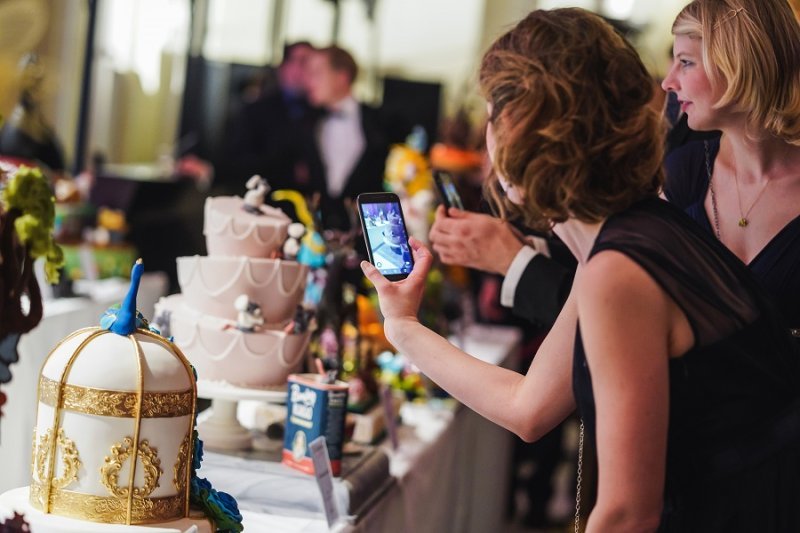 Frau fotografiert die süßen Konditorei-Kunstwerke am Wiener ZuckerBäckerBall