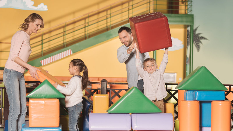 Eltern die mit ihren Kindern in einem Indoor-Spielplatz spielen